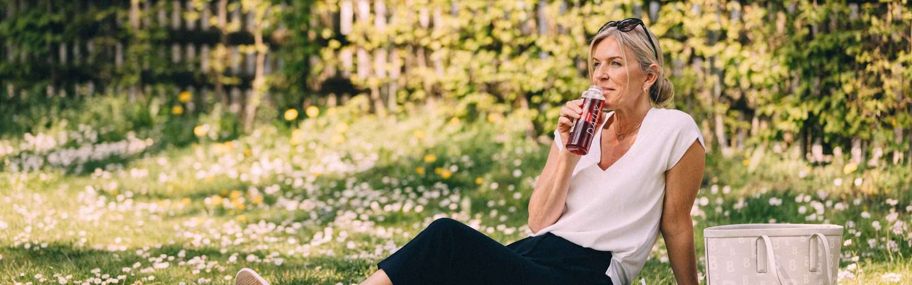 Frau auf einer Wiese am Trinken